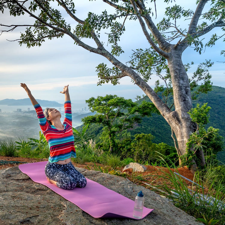 Active woman practicing yoga outdoors on a mountain overlook, representing Wellness Essentials