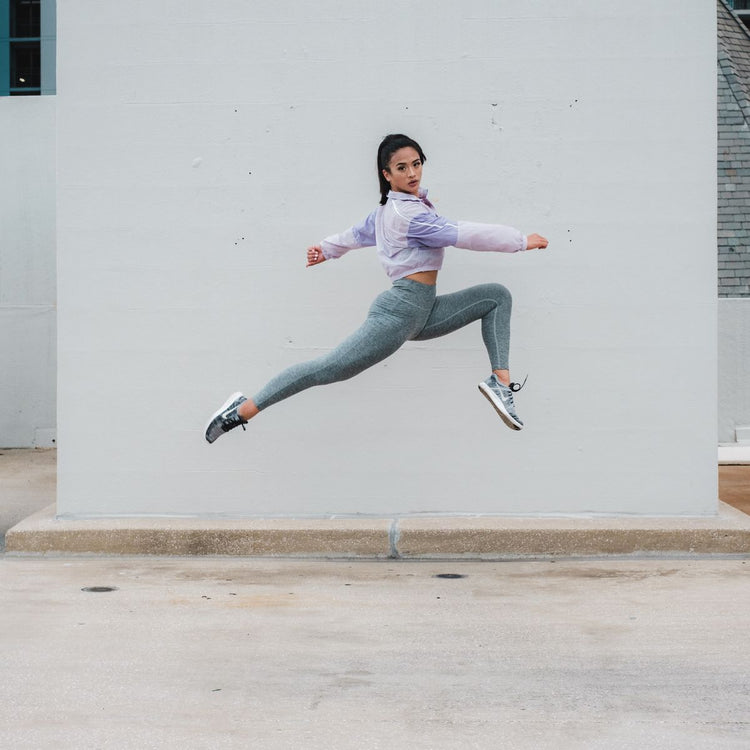 Active woman mid-leap outdoors, representing Women's Health