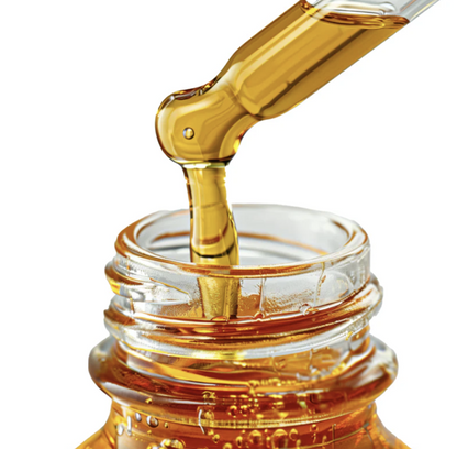 Close-up of a glass dropper dispensing golden Natural Extract Pure Red Tea Moisturizing serum into a bottle.